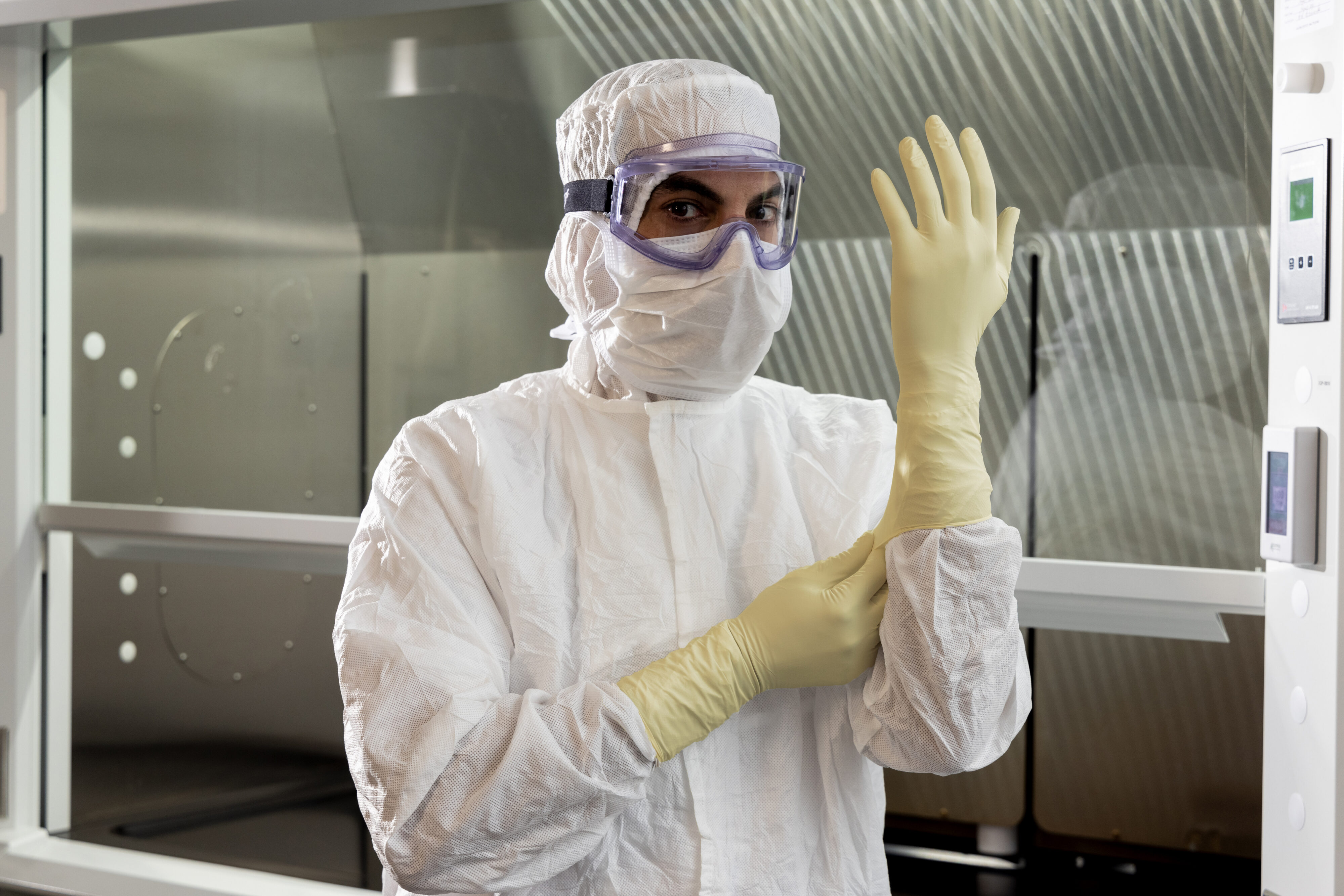 Gloved hands pipetting into culture plates in a sterile pharmaceutical workflow