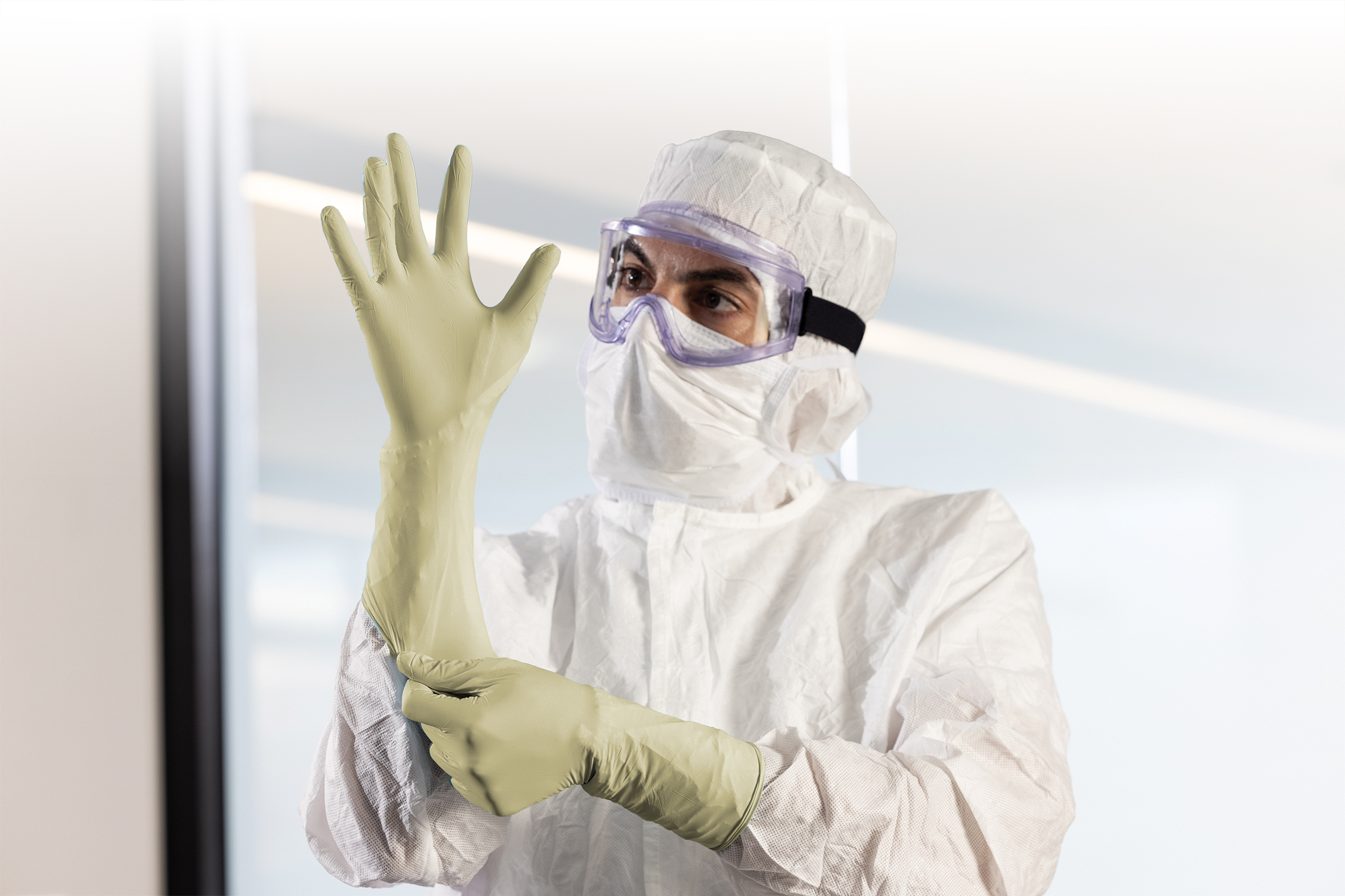 Cleanroom operator in full gowning donning a HALYARD PUREZERO HG3 cream sterile latex glove