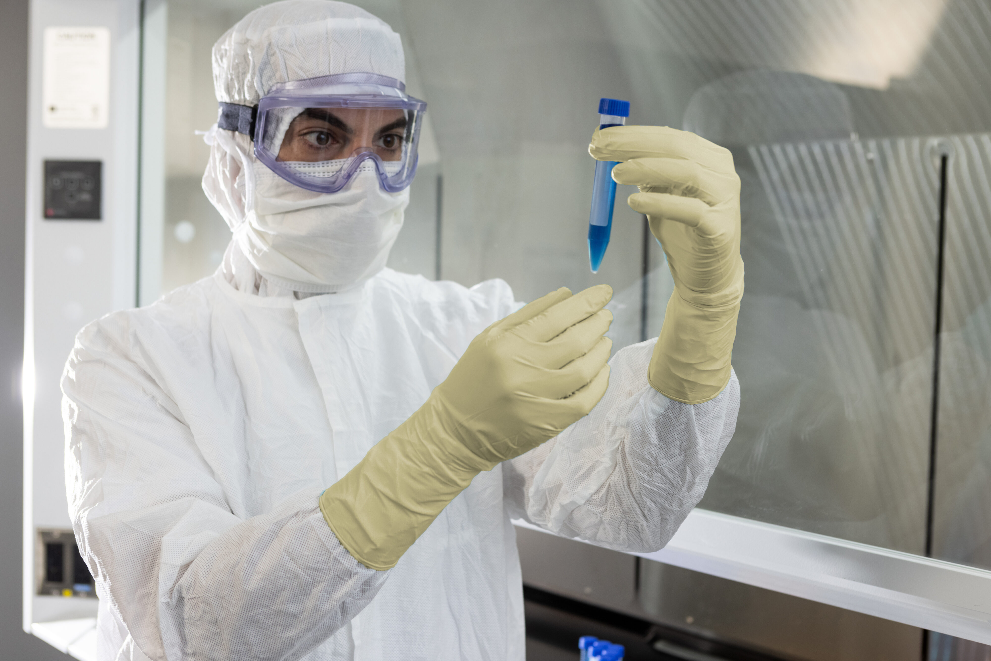 Cleanroom technician in cream latex PUREZERO gloves inspecting a sample vial